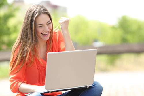 Euphoric woman searching job with a laptop in a park